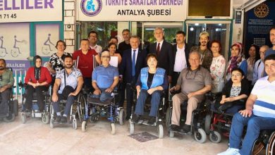 Bu fotoğrafta, Türkiye Sakatlar Derneği Antalya Şubesi önünde toplanmış bir grup insan görülüyor. Ön sırada çoğunluğu tekerlekli sandalye kullanan bireyler yer almakta; arkada ise ayakta duran destekçiler, dernek yetkilileri ve gönüllüler bulunuyor. Çeşitli yaş gruplarından kadın ve erkekler bir araya gelmiş, birlik ve dayanışma duygusu güçlü bir şekilde yansıtılmış. Arka planda derneğin tabelası ve “Aktif Engelliler” yazısı yer alıyor.