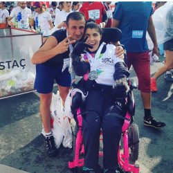 CP'li Büşra Ersoy maraton yarışları sonrası yanındaki erkek gönüllü ile zafer işareti yapıyor.