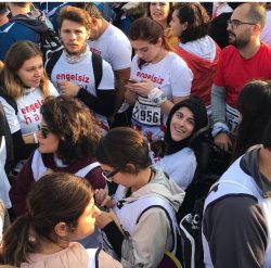 CP'li Büşra Ersoy maraton yarış alanında kalabalık gönüllüler arasında kuş bakışı yukarıya doğru bakarken gülümseyen anı.