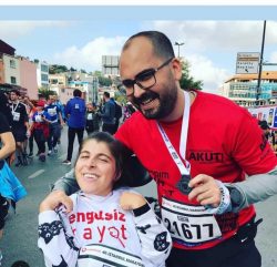 CP'li Büşra Ersoy maraton yarışları sonrası yanındaki erkek gönüllü ile madalyalı gülümseyerek poz veriyorlar.