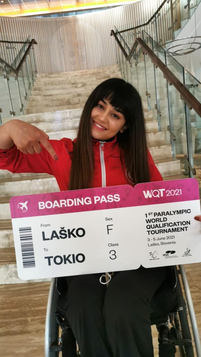 Paralimpik Masa Tenisi Milli Sporcumuz Nergiz Altıntaş elinde büyük boyutlu Tokyo Paralimpik Oyunları biletini mutlulukla gülerek tutuyor.