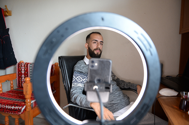 Akıllı telefonu Led halka tripoda takılı rap tutkunu Emir Mervan Dere çalışma masasında oturuyor.