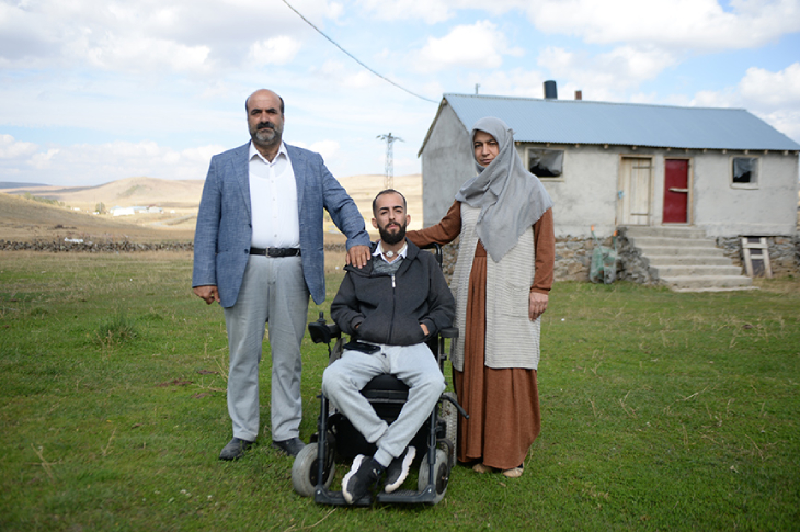 Tekerlekli sandalyede oturan Emir Mervan Dere ile yanında bulunan anne ve babası fotoğraf çektiriyor.