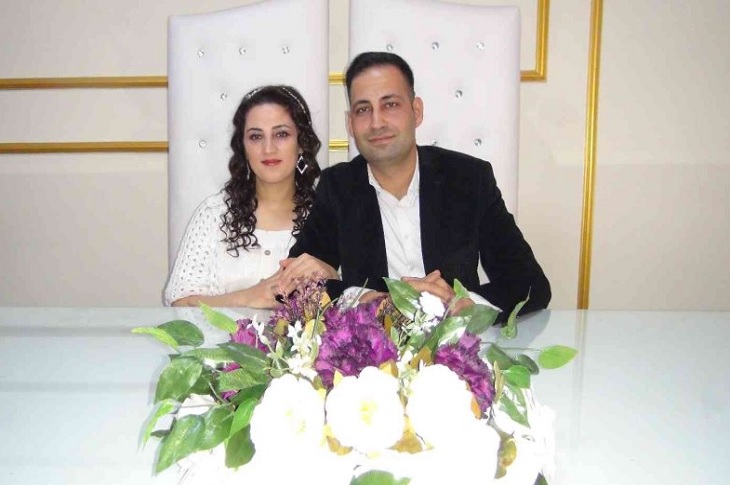 İşitme engelli çift, nikah masasında kol kola tebessümle objektife bakıyor.