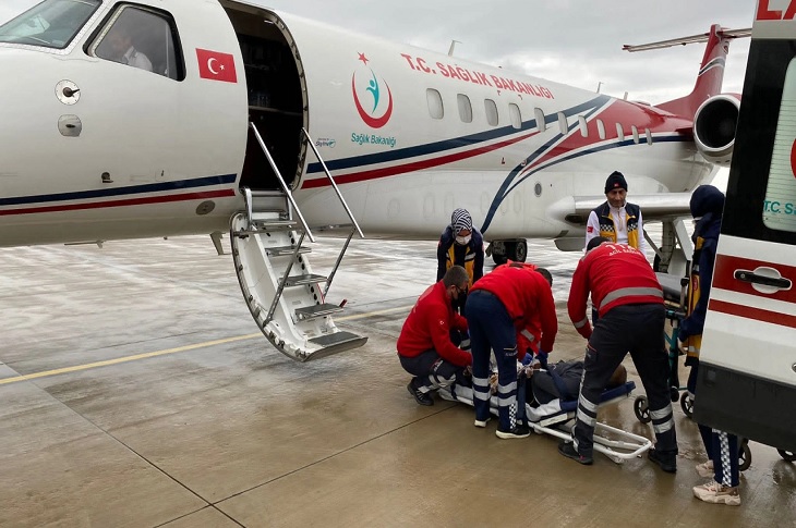 Ambulans aracından ambulans uçağına hasta nakil işlemini yapan görevliler objektife yansıyor.