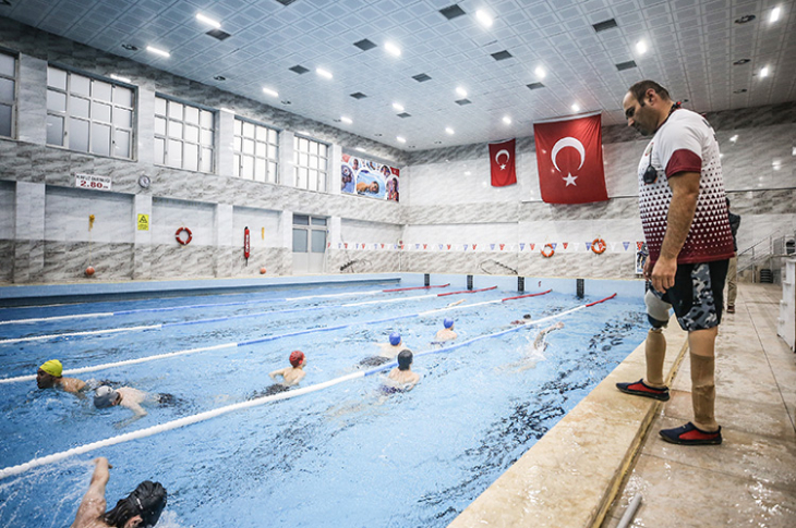 Havuzda yüzen öğrencilerini seyreden öğretmen Ali Uzun.