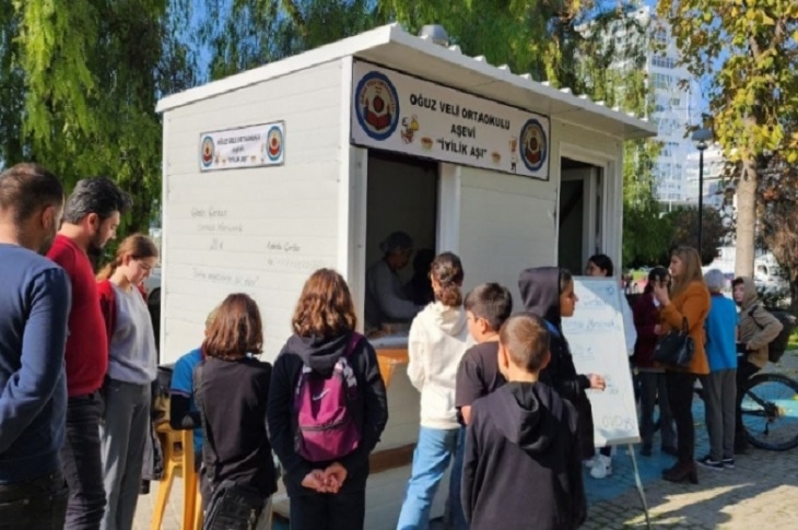 Kurulan aşevi önünde sıraya giren öğrenciler objektife yansıyor.