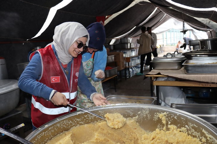 Firdevs, yemek çadırındaki helva kazanının başında helvayı karıştırıyor.