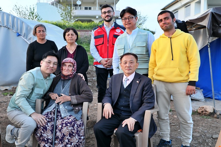 Depremzede Kore Gazisi'nin çadırını ziyaret eden Koreli Ekipler toplu hatıra resmi ile objektife yansıyor.