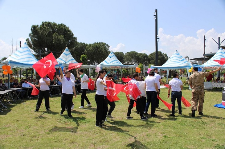 Çimen üzerinde ellerindeki Türk bayraklarıyla oyun havasında oynayan çok sayıda engelli çocuk objektife yansıyor.