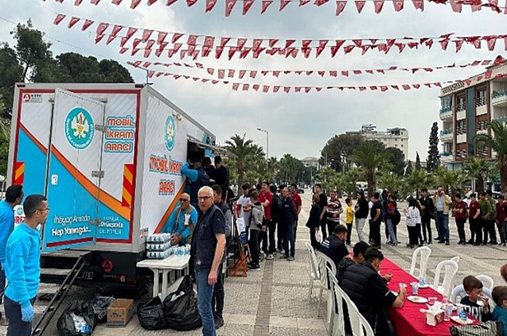 Mobil ikram aracından dağıtılan pilav için sıraya giren çok sayıda katılımcı vatandaş objektife yansıyor.