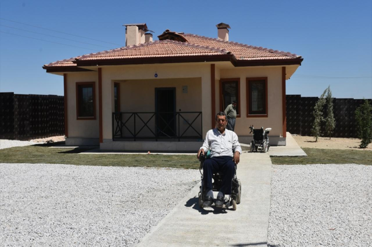 Depremzede Ali Seydi Fırat konutun önünde yapılan yaya yolunun üstünde tekerlekli sandalyesinde oturuyor.