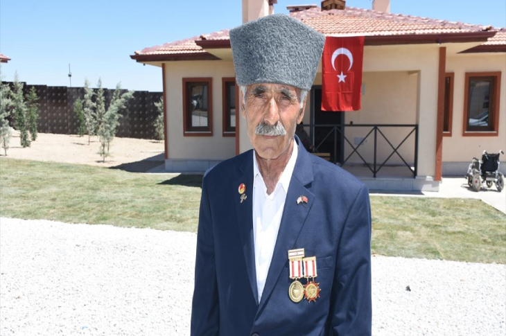 Kıbrıs gazisi depremzede Mehmet Karadaş, inşa edilen konutun önünde bulunuyor.