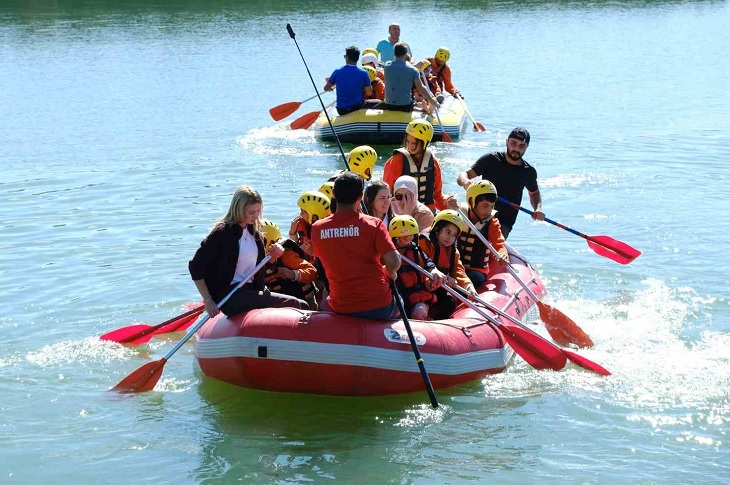 Aynı botta rafting yapan özel gereksinimli çocuklar objektife yansıyor.