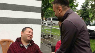 Etkinlikte tekerlekli sandalye kullanıcısı bedensel engelli bir birey ile görevli bir kişi el sıkışıyor.