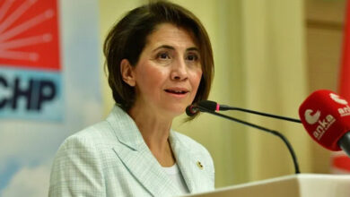 Aylin Yaman, kürsüde mikrofonlara doğru konuşuyor.