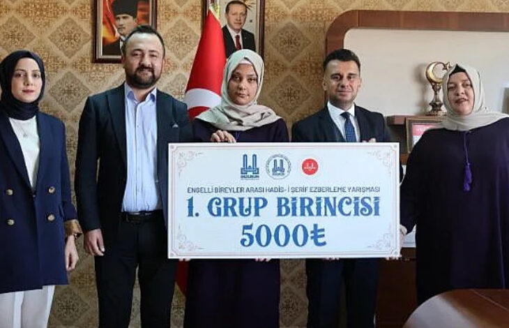 Engelli Bireyler Arası Hadis-i Şerif Ezberleme Yarışması'nı düzenleyen kişiler ve ödül çeki ile yarışmayı kazanan engelli birey fotoğraf çekiliyor.