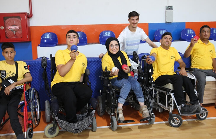 Serebral palsili öğretmen Yavuz Öndem, tekerlekli sandalye kullanıcısı sporcular ile birlikte fotoğraf karesinde yer alıyor.