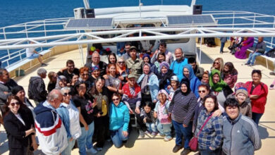 Ayvalık Belediyesi etkinlik yetkilileri, STK'lar ve engelli bireyler teknede fotoğraf çektiriyor.