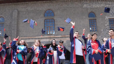 Engelli öğrenciler büyük bir coşkuyla havaya keplerini atıyorlar.