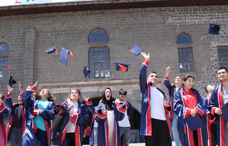 Engelli öğrenciler büyük bir coşkuyla havaya keplerini atıyorlar.