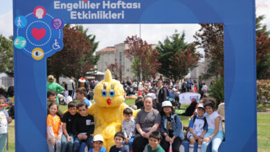 Etkinlik alanında civciv kostümü giyen kişinin etrafında, engelli çocuklar var.