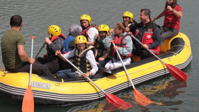 Suyun üstünde 10 kişilik bir ekiple birlikte engelli bireyler rafting yapıyor.