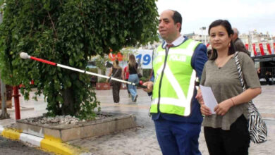 Görme engelli birey karşıdan karşıya geçerken beyaz bastonu havaya kaldırarak yol önceliği alıyor.