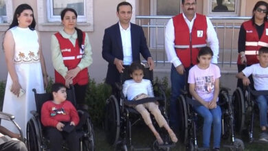 Tekerlekli sandalyeler üzerinde engelli çocuklar önde, Kızalay görevlilere ve Silopi Kaymakamı tekerlekli sandalyelerin arkasında fotoğraf çekiliyor.