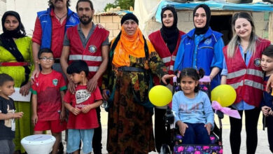 Akülü tekerlekli sandalye üzerinde oturan Mahide İzgiş, ailesi ve gönüllü gençler ile fotoğraf çekiliyor.