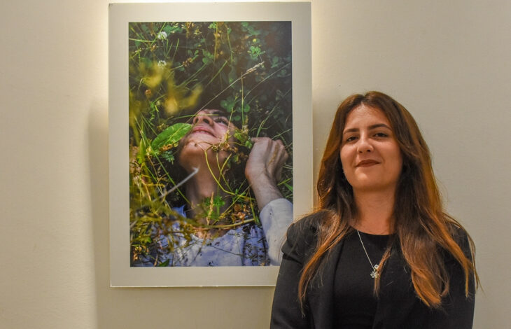 Melisa Şener sergide gösterilen eserlerden birinin yanında duruyor.