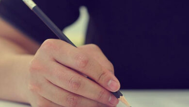 Kurşun kalem ile yazı yazan bir el var.