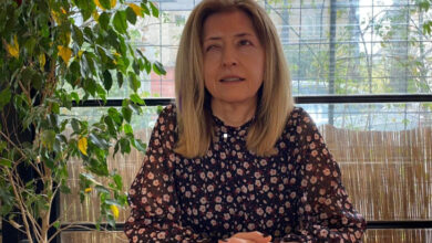 Özlem Kara önünde bulunan masada ellerini tutarak oturmaktadır.