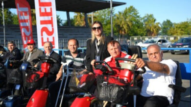 Samsun Büyükşehir Belediyesi akülü tekerlekli sandalye dağıtımını yapan görevliler ve engelli bireylerle fotoğraf çektirmek için poz veriyorlar.