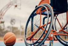 Basketbol sahasında boş bir tekerlekli sandalye ve yanında bir basketbol topu var.