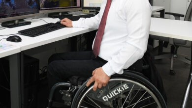 Tekerlekli sandalye kullanıcısı engelli birey masa başında bilgisayar kullanıyor.