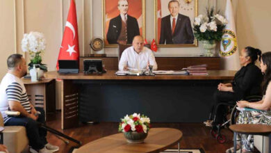 Yüreğir Belediye Başkanı Ali Demirçalı, makam koltuğunda oturuyor ve engelli personeli ile konuşuyor.