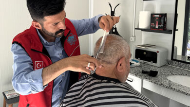 Yaşlı bir birey, erkek berberinde saçını kestiriyor.