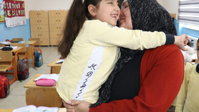 Bedensel engelli Ayşenur Gedik, annesi Satı Gedik'in kucağında birbirlerine gülümseyerek sarılıyorlar.