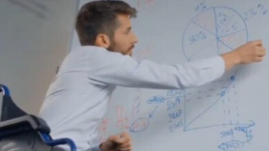 Tekerlekli sandalye kullanıcısı engelli öğretmen, beyaz tahta önünde bazı matematik formülleri yazıyor.