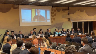 Birleşmiş Milletler (BM) İnsan Hakları Konseyinin 56'ncı Oturumu'nda ülkelerin üyeleri ve temsilcileri masa etrafında otururken projeksiyon ekranına bir görsel yansıtılıyor.