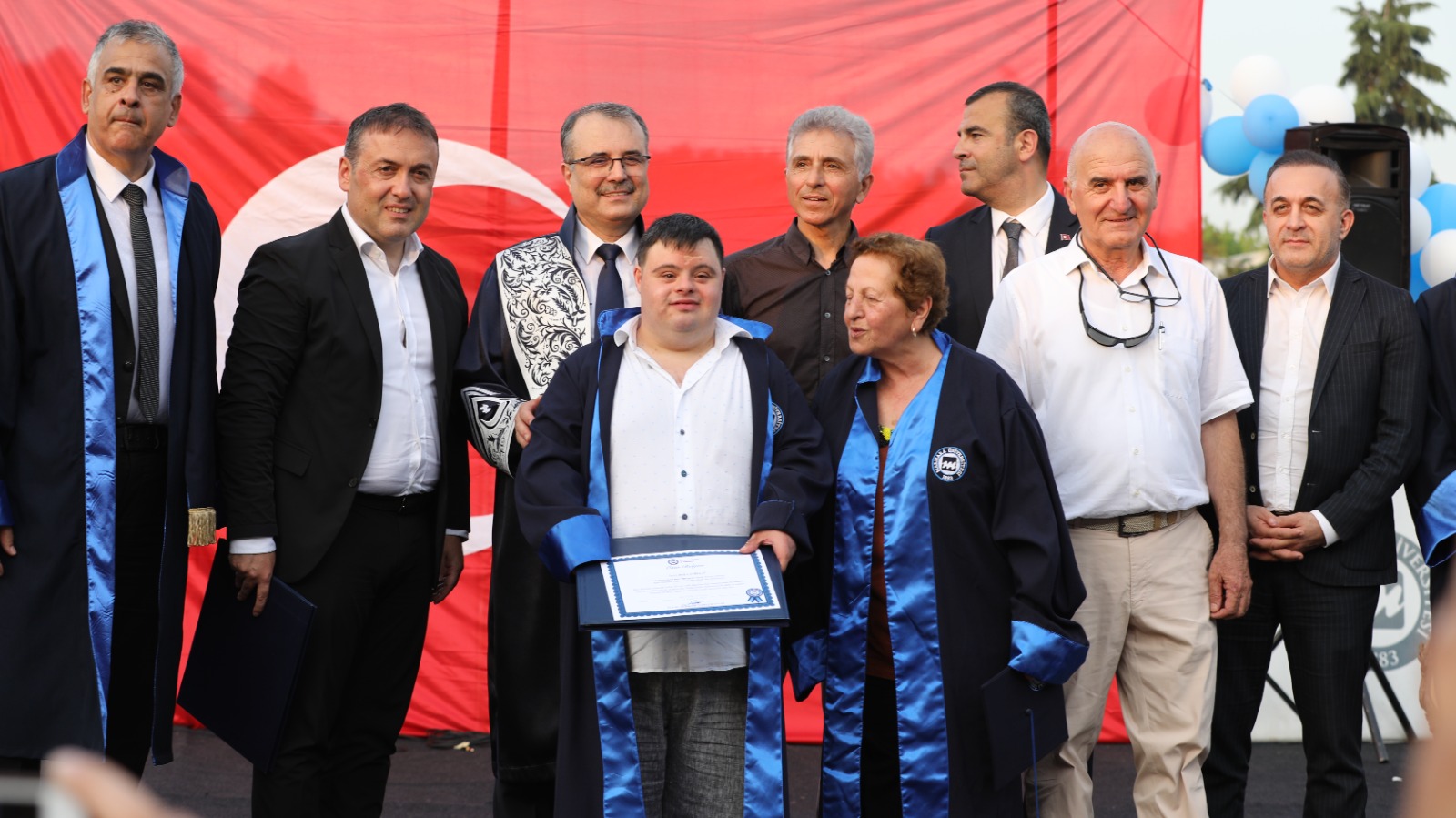 Görselde down sendromlu Berk Canbulat'a diploma veriliyor ve yanında ailesi ile hocaları var.