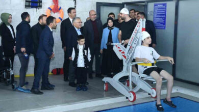 Kayseri Büyükşehir Belediye Başkanı Dr. Memduh Büyükkılıç ve görevliler konuşuyor. Engelli bireyde özel bir aparat yardımıyla havuzun üzerinde tutuluyor.