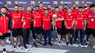 Ampute Futbol Milli Takım sporcuları koltuk değneği üzerinde gri bir futbol topu şeklindeki kupa etrafında, yan yana durarak toplu fotoğraf çekimi yapılıyor.