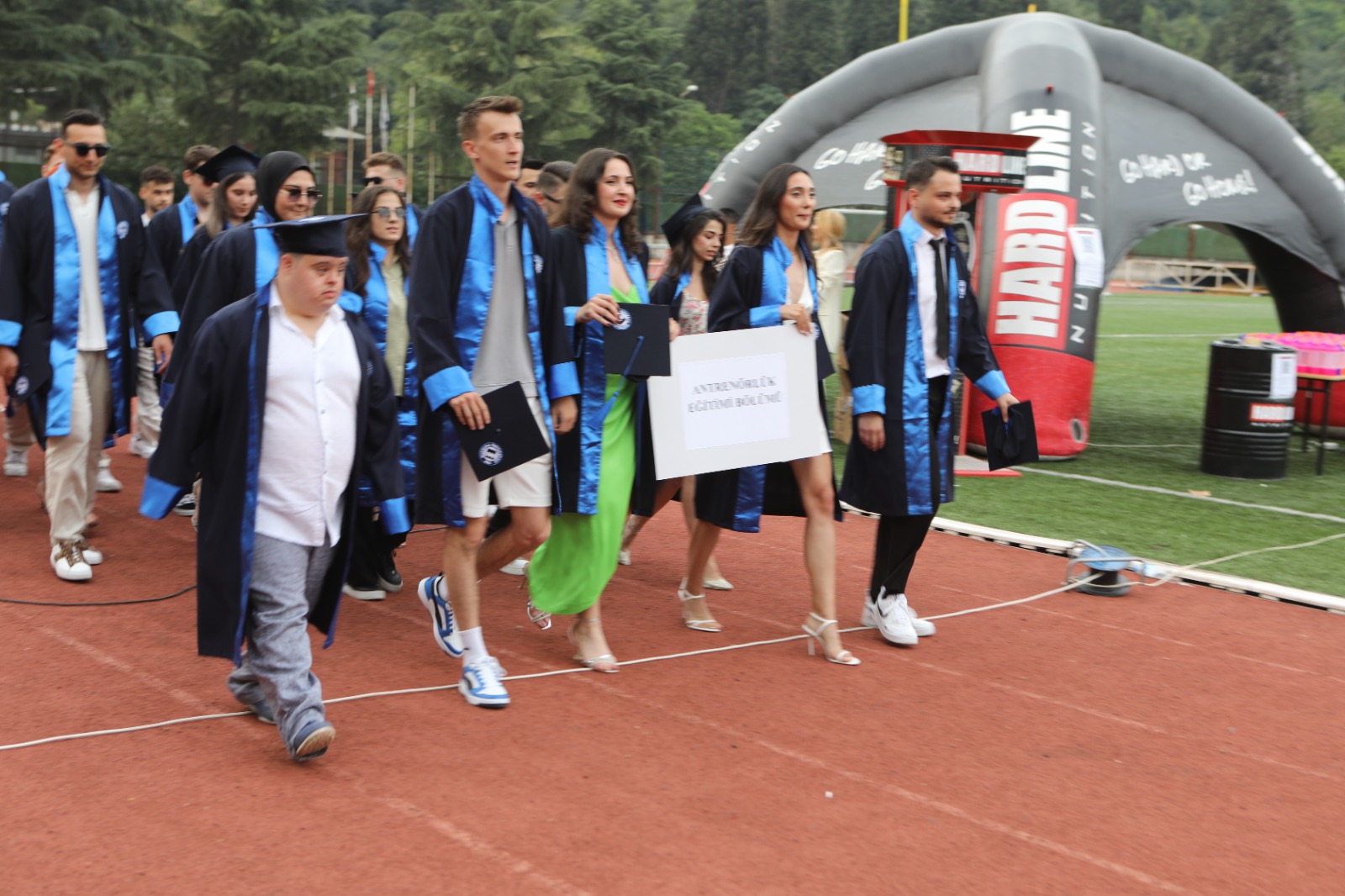 Down sendromlu Berk Canbulat ve arkadaşları cüppe ile kepleriyle, ellerindeki pankartla yürüyorlar.