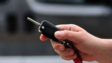 Bir kişinin elinde siyah renkli bir anahtar tutacağı üzerindeki tuşa basarak otomobilin kilit sistemini değiştiriyor.