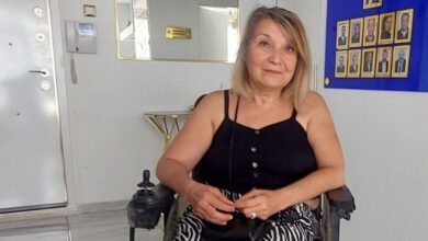 Akülü tekerlekli sandalyede oturan Nursel Köylücü'nün fotoğrafı karşısından, beyaz renkli duvarları olan bir odada çekilmiş.