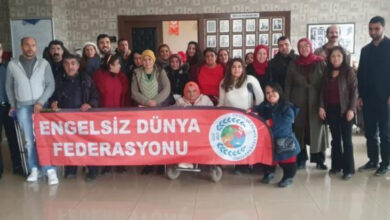 "Engelsiz Dünya Federasyonu" yazılı büyük kırmızı bir pankartın arkasında farklı yeti kayıpları olan engelli bireyler toplu fotoğraf çekimi için yan yana durmuşlar.