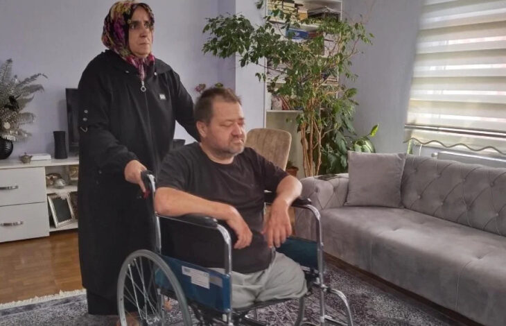 Her iki ayağı ampute bedensel engelli bir adam tekerlekli sandalye üzerinde ve ayakta duran arkasında bir kadın var.