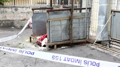 Fotoğrafta zemin üzerinde duran yük asansörü ve olay yeri inceleme şeridi çekilmiş.